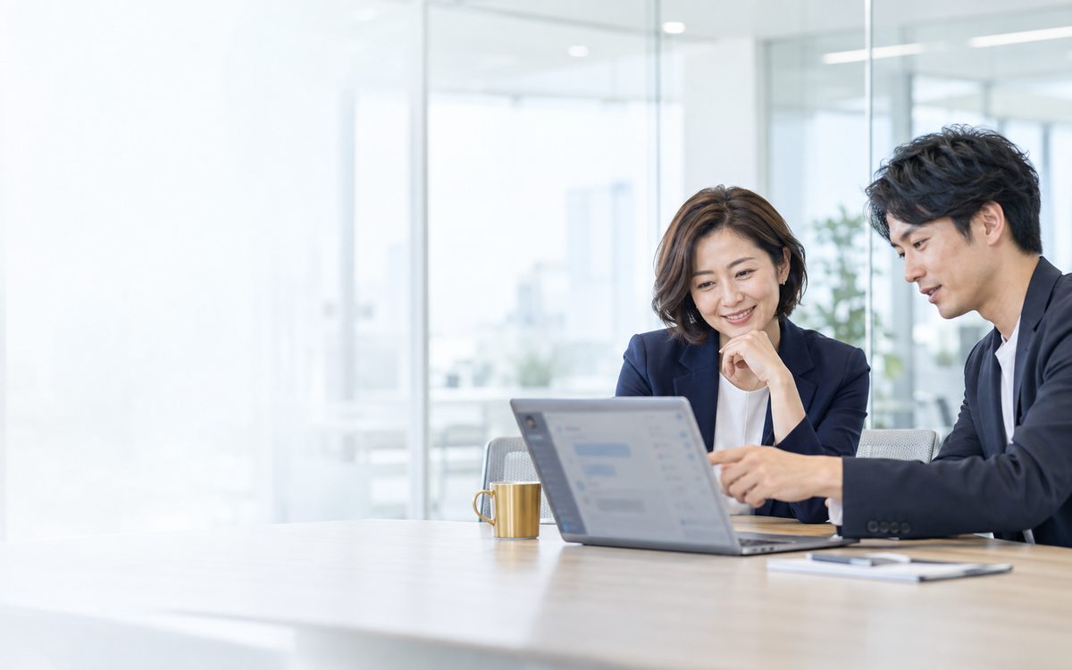 ノートPCの仕様解説BOTを見ながら打ち合わせをする2人(イメージ)